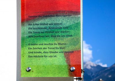 Text auf Eckverglasung der Südtirolersiedlung in Absam mit Blick in die Berge © Gestaltung Hilde Chistè © Aufnahme Dorfstterer
